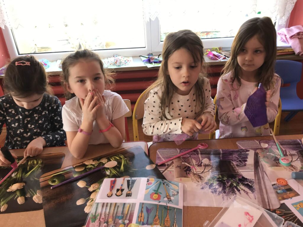 Dzieci tworzą przy stolikach własne kukiełki.