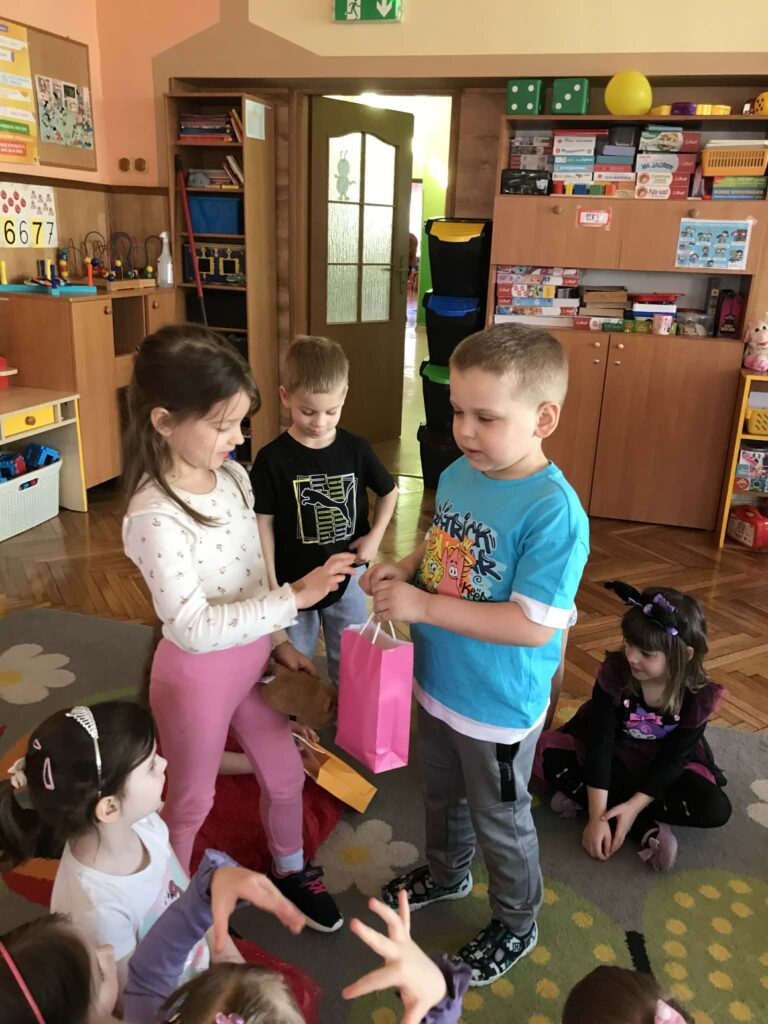 Chłopiec wręcza upominek dziewczynce.