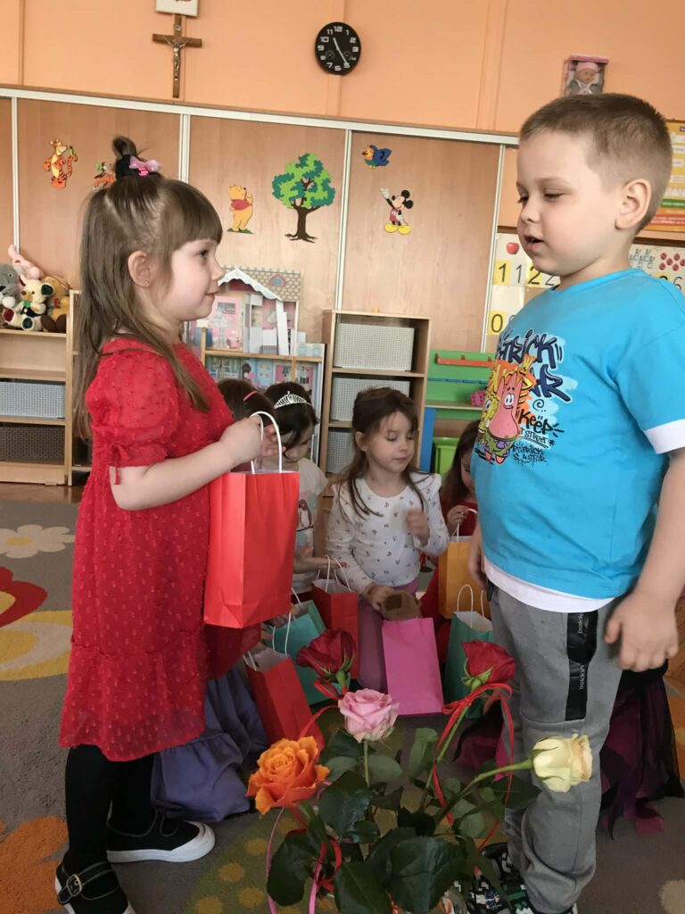 Chłopiec wręcza upominek dziewczynce.