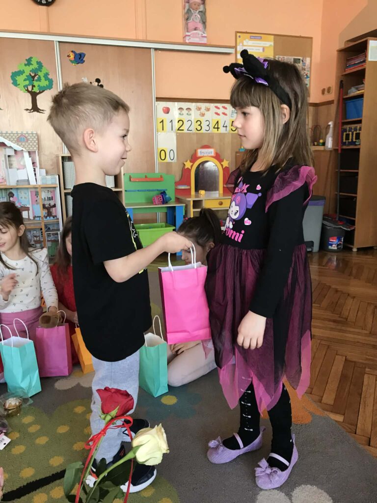 Chłopiec wręcza upominek dziewczynce.