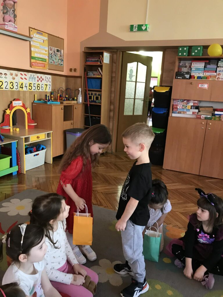 Chłopiec wręcza upominek dziewczynce.